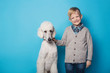 Fashionable boy with dog. Friendship. Pets. Studio portrait over blue background