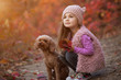 Little girl sitting with dog together on nature at the autumn day, art portrait